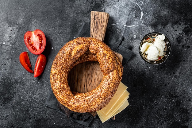 Bagel Simit ou Gevrek sur planche de bois pour la cuisson des sandwichs. Fond noir. Vue de dessus.