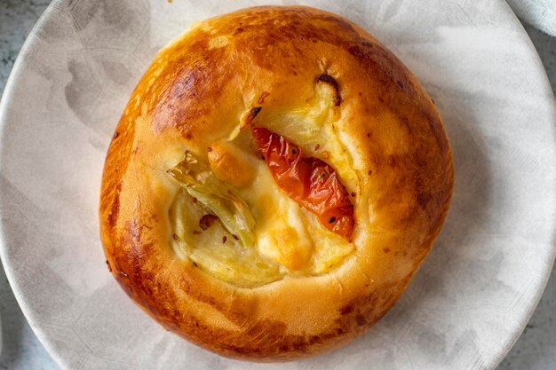 Photo bagel turc pogaca avec tomate cheddar et poivre arômes traditionnels pogaca sur fond gris vue supérieure