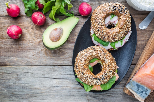 Bagels au cream cheese avocat, poisson, roquette et radis. Aliments sains pour le petit-déjeuner. Vue de dessus.