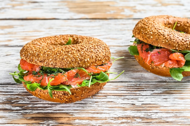 Bagels au saumon, crème, avocat et roquette. Fond en bois blanc. Vue de dessus.