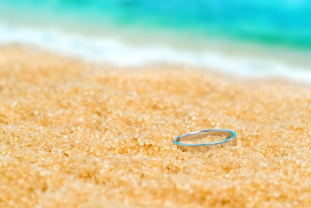 Bague en argent dans le sable sur le fond de la plage et de la mer