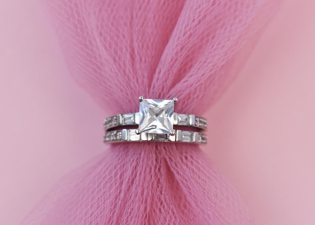 Une bague de bijoux avec un diamant d'argent sur un fond rose