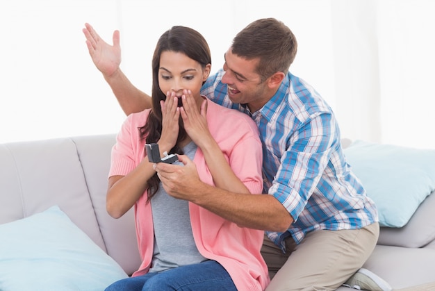 Bague de cadeau homme à une femme surprise sur le canapé