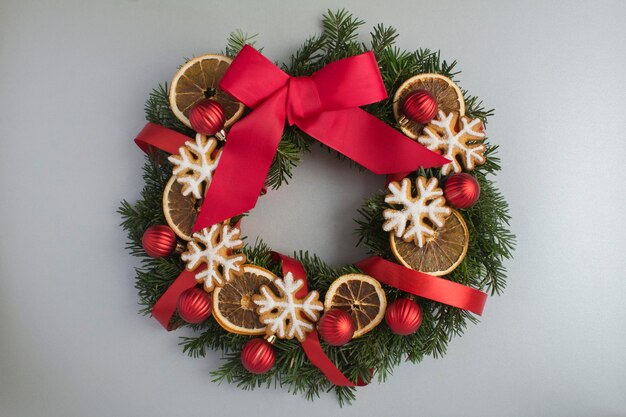 Bague ou couronne de Noël avec boules rouges, pain d'épice et orange séchée sur fond gris. Vue de dessus. Fermer.