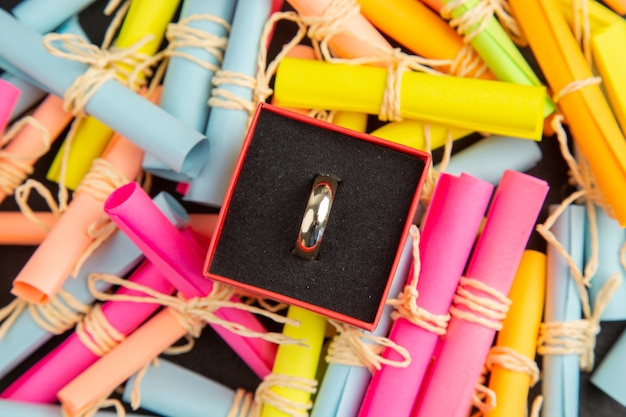 bague de fiançailles vue de dessus dans une boîte sur des papiers de souhaits de défilement