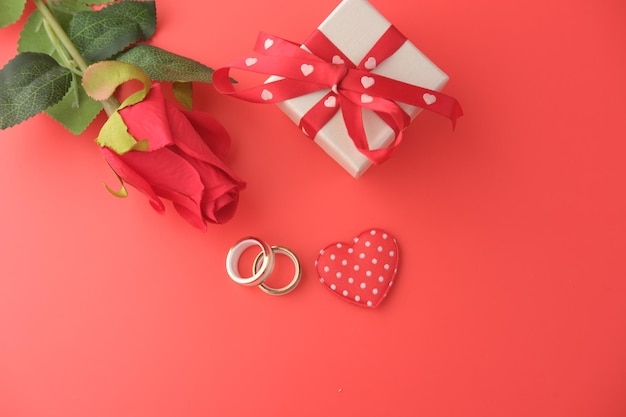 Bague de mariage et coffret cadeau et fleur rose sur rouge