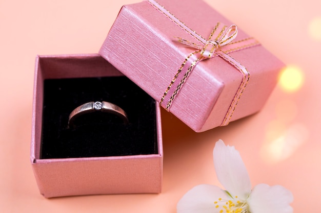 Photo une bague de mariage dans une petite boîte fabriquée sur un fond de corail mou.