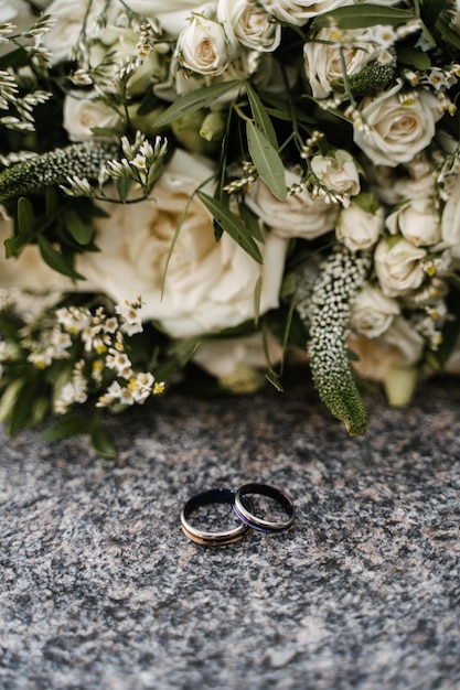 Les bagues de fiançailles de mariage en argent et en pierre sombre reposent sur une surface en granit contre