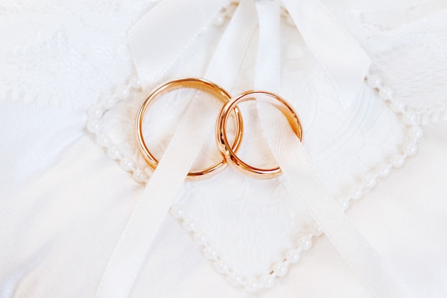 Bagues de mariage dorées sur fond de soie blanche. Détails de mariage. Symbole de l'amour et du mariage.