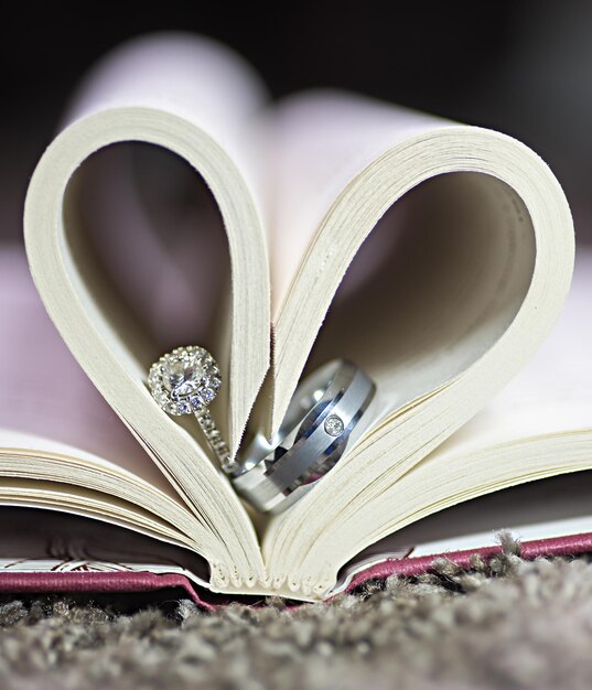 Photo les bagues de mariage de la mariée et du marié dans un livre en forme de cœur