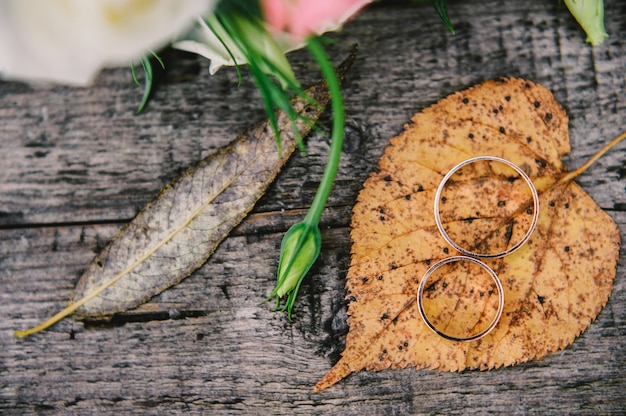 Bagues de mariage or sur congé et fond de texture en bois