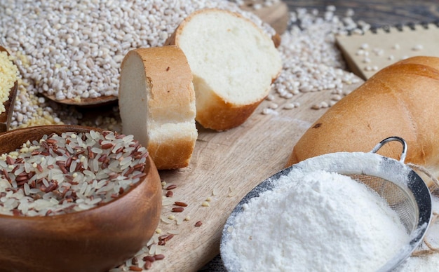 Une baguette de blé sur la table avec de la farine et diverses céréales végétales une table de cuisine avec du pain et des ingrédients pour la bouillie et le riz