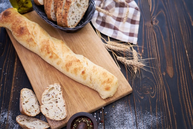 Baguette fraîche et pain tranché sur une planche à découper en bois à la table de la cuisine