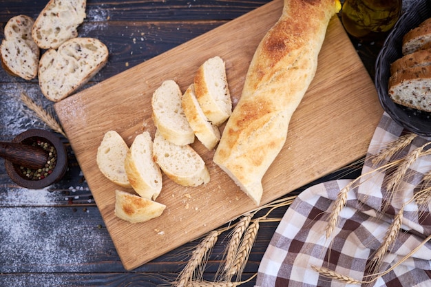 Baguette fraîche et pain tranché sur une planche à découper en bois à la table de la cuisine