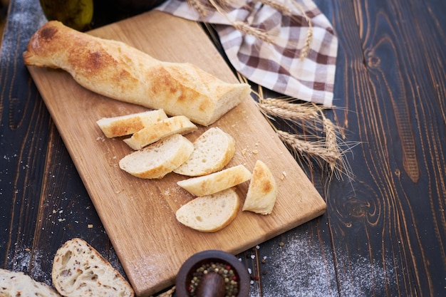 Baguette fraîche et pain tranché sur une planche à découper en bois à la table de la cuisine