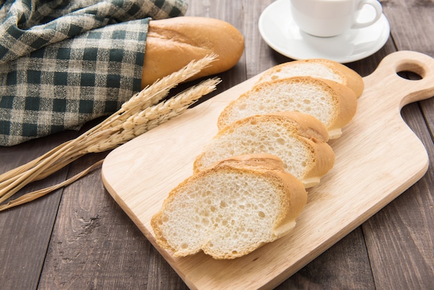 Baguette fraîchement cuite au four et tasse de café sur la table en bois