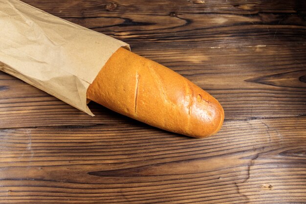 Photo baguette française dans un sac en papier sur une table en bois