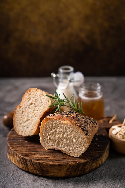 Baguette de pain frais au pain entier, au lait blanc et au miel sur une planche de bois rustique