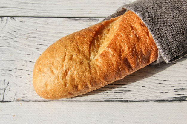 Baguette de pain frais français sur serviette et fond en bois