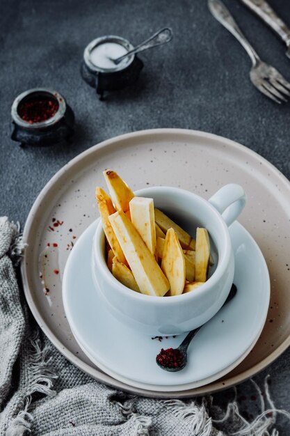 Photo des baguettes crues, des tranches de pommes de terre douces dans une tasse de porcelaine, des recettes rapides d'igname maison, de la nourriture de campagne.