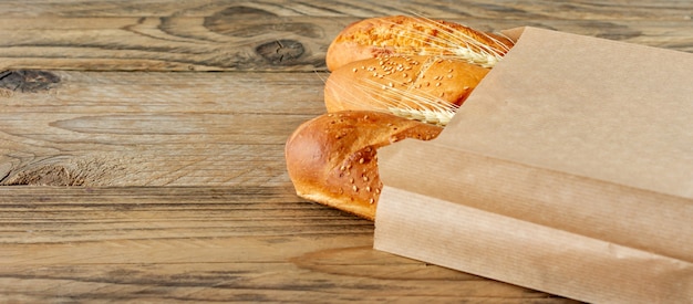 Photo baguettes françaises disposées dans un sac en papier et du blé sur une table en bois rustique.