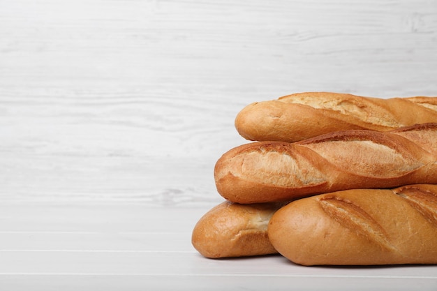 Baguettes savoureuses sur table en bois blanc Espace pour le texte