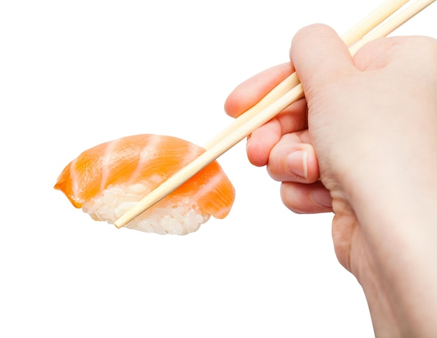 Les baguettes tiennent les sushis nigiri au saumon en gros plan