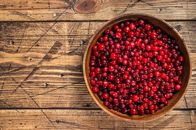 Baie de canneberge rouge dans une assiette en bois