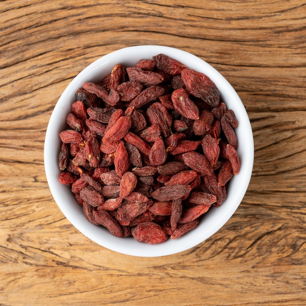 Baie de Goji dans un bol sur une table en bois.