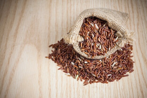 Baie de riz dans un sac sur un fond en bois.