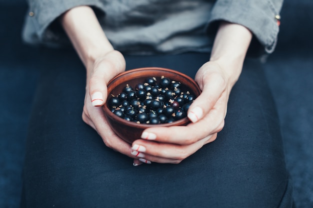 Baies de cassis en plaques dans des mains féminines. Vitamines et concept d&#39;alimentation saine