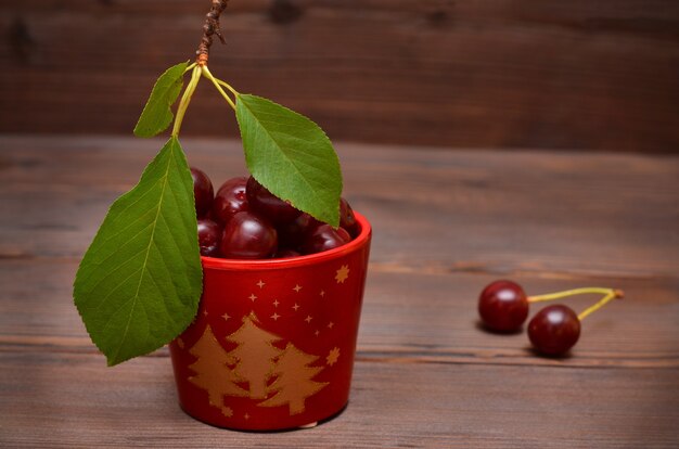 Baies de cerises fraîches dans un pot de Noël rouge sur fond de bois