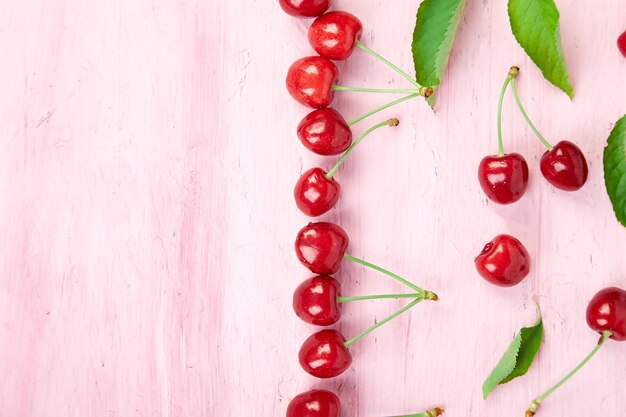 Baies de cerises mûres et feuille de cerisier sur fond rose