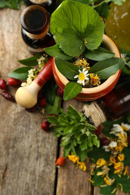 Baies et fleurs d'herbes avec du mortier sur le fond de table en bois