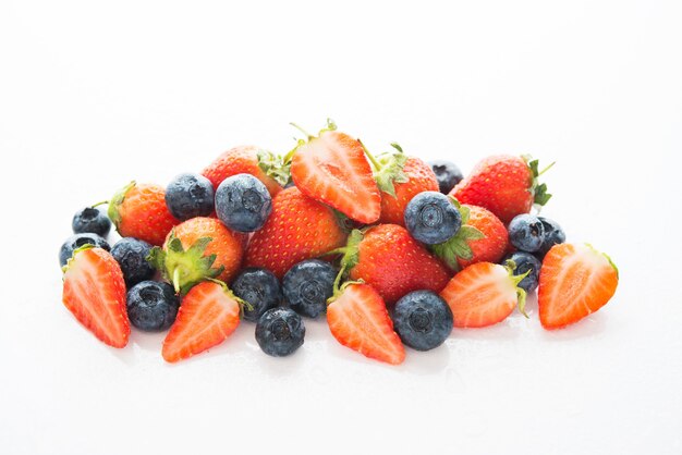 Baies fraîches d'été, fraises et myrtilles en gouttes d'eau, isolés sur blanc