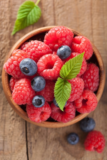 Baies fraîches myrtille framboise dans un bol en bois