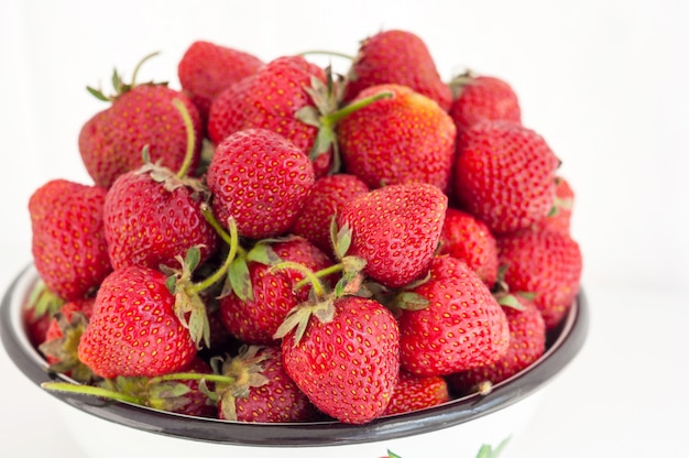 Baies de fraise se bouchent dans un bol rustique sur fond blanc. Mise au point sélective