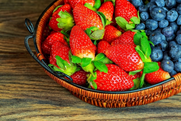 Baies et fraises saines dans un panier en bois fond