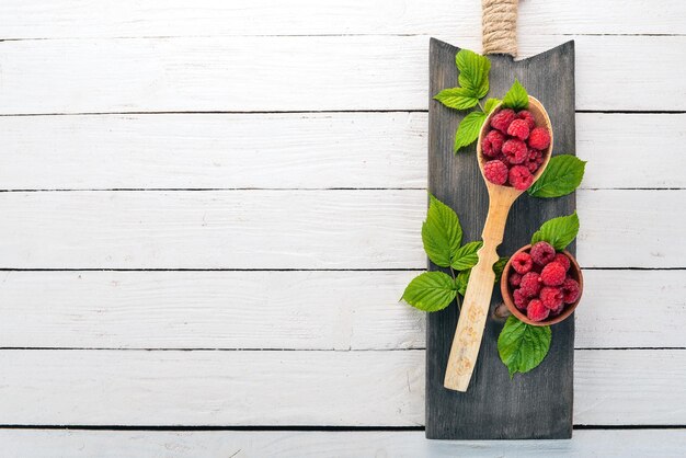 Baies de framboise dans une cuillère en bois Sur un fond en bois Vue de dessus Espace libre pour votre texte