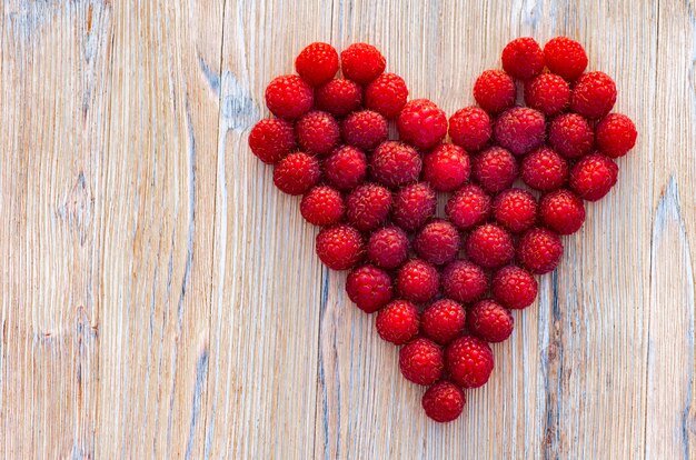 Baies de framboise sur un fond en bois. Coeur de baies.