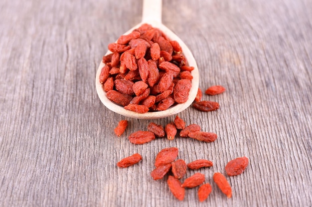 Baies de Goji dans une cuillère en bois sur fond de bois