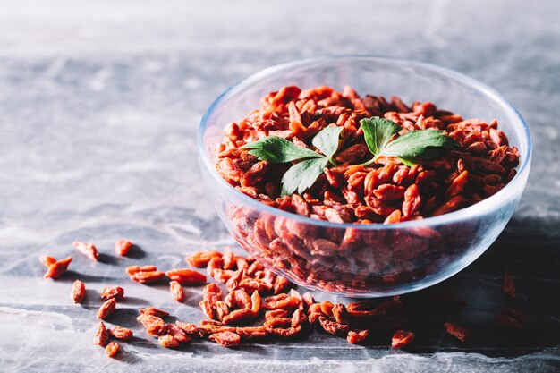 Baies de Goji et feuilles vertes dans un bol en verre