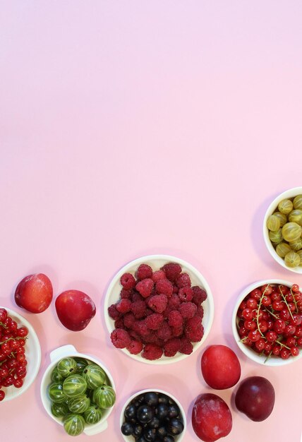 Baies mélangées dans une assiette en béton sur fond rose avec assiette vide et espace de copie