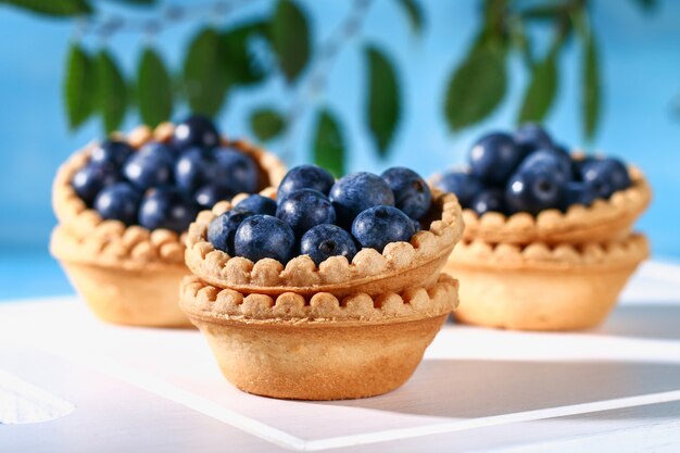 Baies de prunellier bleu dans des tartelettes de sable sur une table.