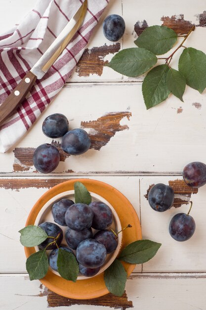 Baies de prunes fraîches sur une assiette avec des feuilles