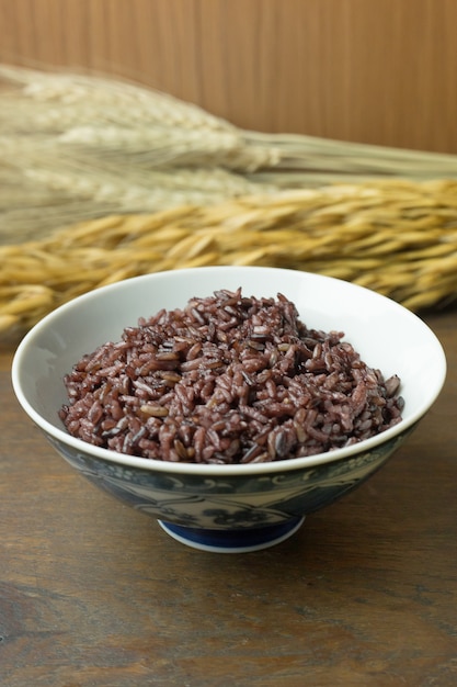 Baies de riz cuites, riz à grains entiers Thai riz au jasmin noir dans un bol sur une table en bois.