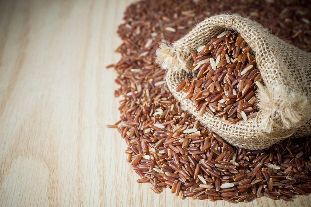 Baies de riz dans un sac sur un fond en bois.