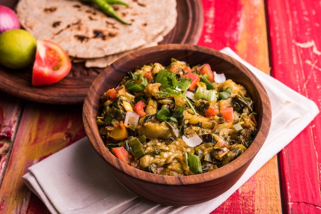 Baigan /Baingan Bharta - Purée d'aubergines rôties cuites avec des épices et des légumes. Servi avec du pain plat à la farine de Jowar connu sous le nom de bhakar/bhakri. servi sur fond coloré ou en bois