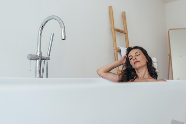 Baignade femme relaxante dans le bain avec les yeux fermés