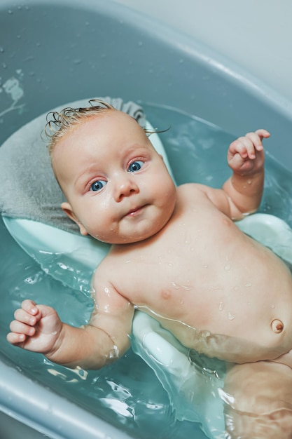 Baigner un bébé dans une baignoire sur un support Le premier bain d'un bébé à la maison après sa naissance
